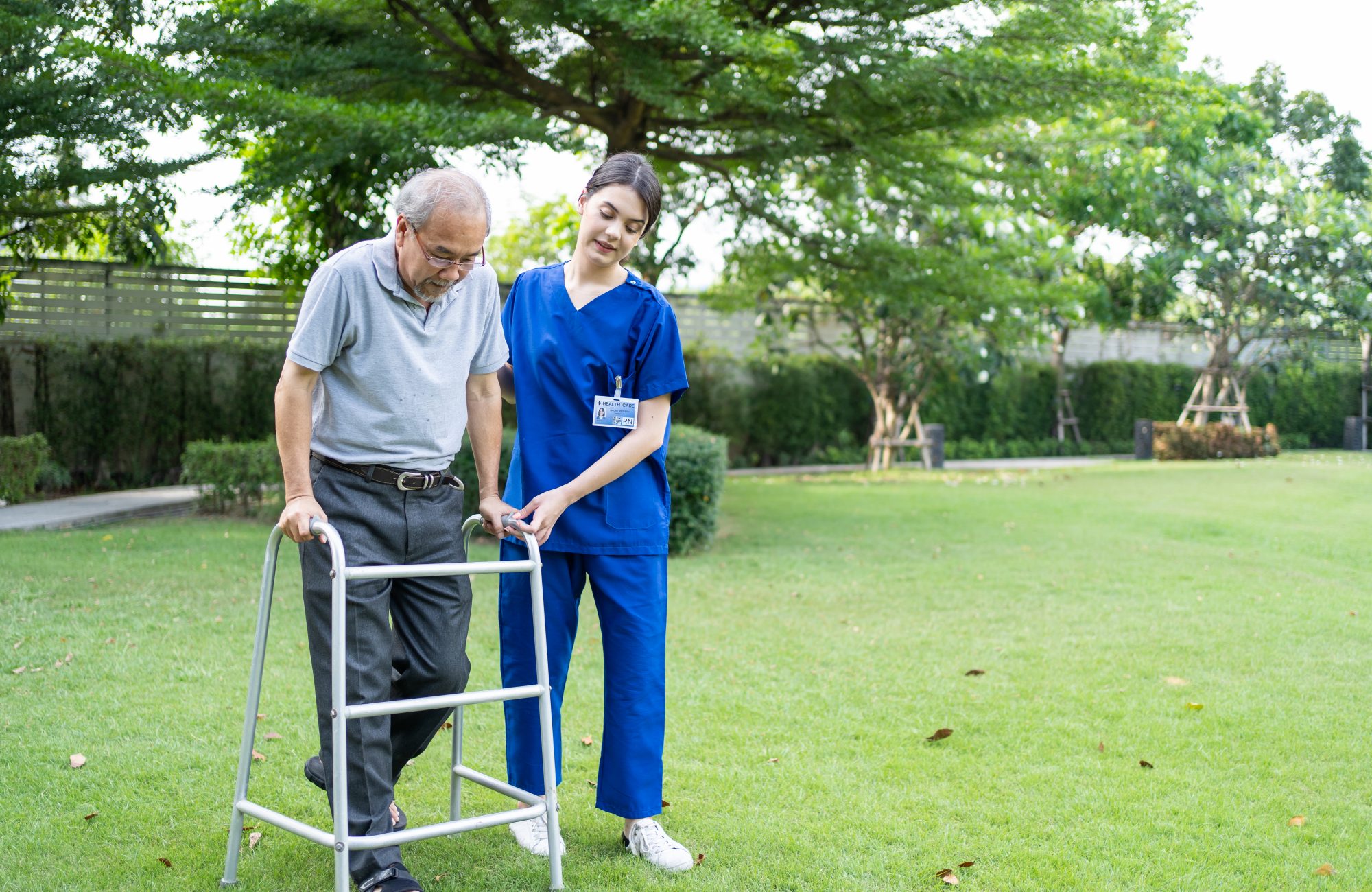 Asian young woman nurse at nursing home take care disabled senior man at backyard.